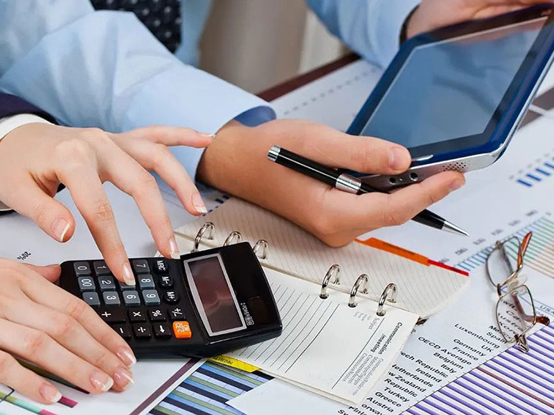 two hands holding a calculator and a tablet